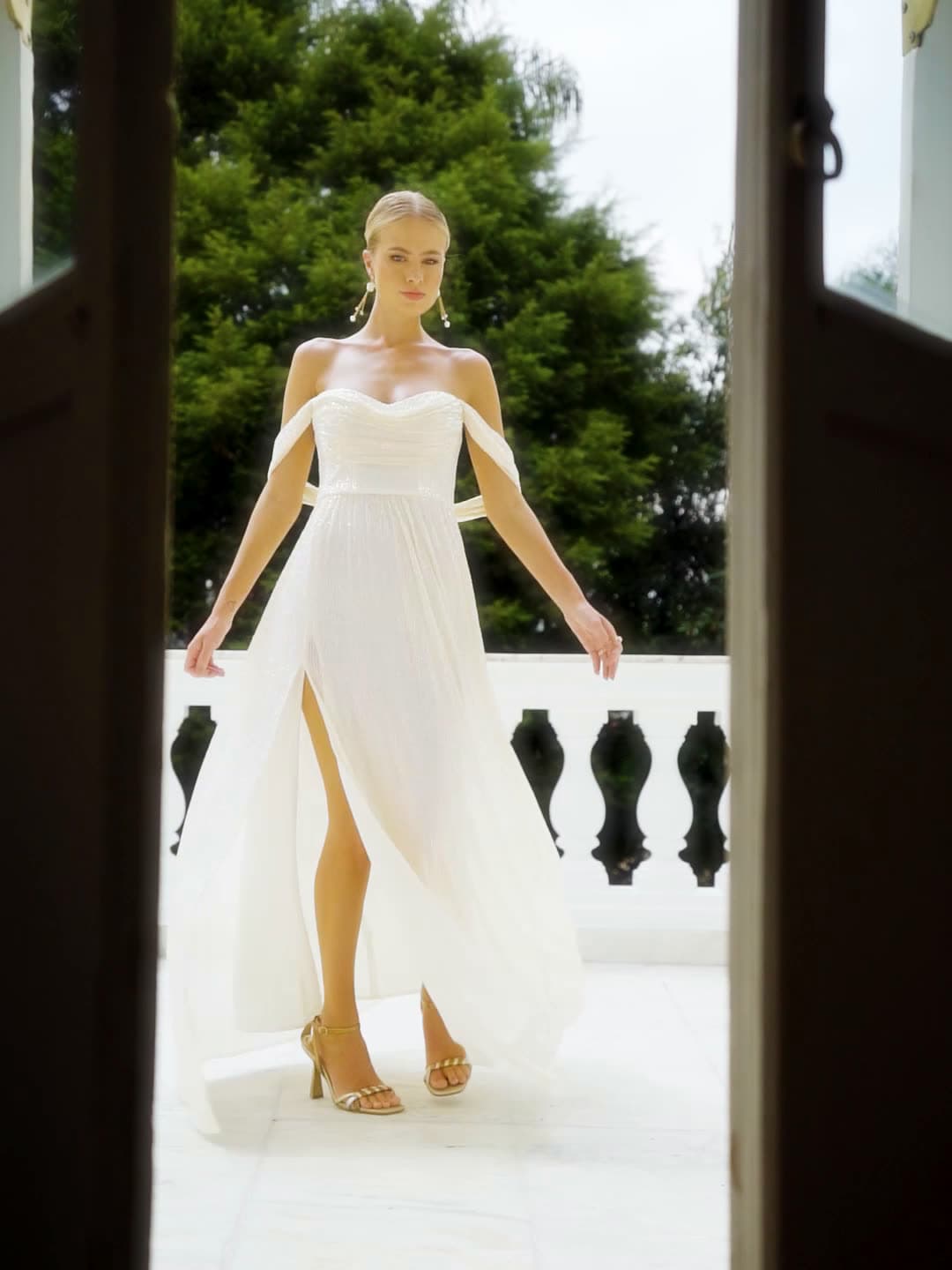 Vestido branco de ombros caídos no terraço do casarão